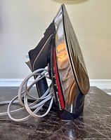 Side view of Rowenta ProMaster XCel Steam Iron showing black and silver body, red accent, and coiled power cord.