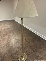 Full view of brass floor lamp with cord and shade