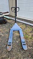 Front angled view of blue hand pallet jack with black handle and visible rust wear.