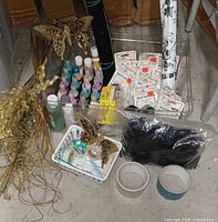 Overall view of stencil paints, decorative tapes, and metal butterfly decorations laid out on floor.