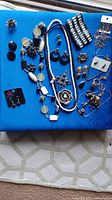 Full lot of miscellaneous black and white jewelry laid out on a blue surface including earrings, bracelets, necklaces, rings, and pins.