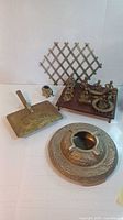 Full shot showing brass ashtray, musicians figurines on wooden base, brass expandable coat hanger, brass tray with handle, small elephant figurine and small circular brass item.
