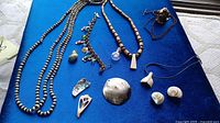 Overview of all jewelry items laid on blue surface including necklaces and pendants