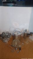 Full barware set including glass goblets on stand, ice bucket, shaker and tools on a brown carpet background