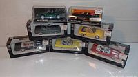Seven 1/43 scale die cast convertibles in original boxes arranged on a white surface. Boxes are black with clear windows, showing detailed car models inside.