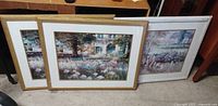 Three framed and matted watercolor prints leaning against a wall, two with wood frames and one with a white frame.