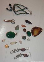Overhead photo showing entire lot of various handmade jewelry pieces: pendants, earrings, and a beaded bracelet, arranged on white surface for clear view.