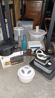 Overview of various kitchen gadgets including noodle strainer, patty maker, pitchers, mini oven box, storage containers, vintage nut grinder.