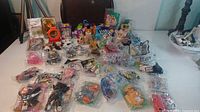Wide view of assorted McDonald's toys, sealed and loose, on a table showing various franchises and packaging