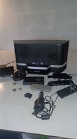 Main Sirius XM radio speaker unit with remotes, power adapter, and various attachments spread on flat surface.