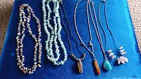 Image of 8 stone jewelry necklaces on blue background showing detail of beads and pendants.