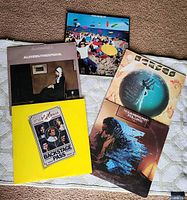 Five vinyl albums arranged on fabric showing album covers of various titles and artists.