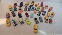 Overview photo showing all 30 vintage toy cars spread out on a white surface, highlighting variety in models and colors.