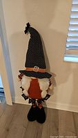 Front view of Halloween gnome with tall black polka dot hat and orange and black striped sleeves and legs