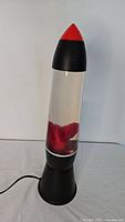 18-inch lava lamp with black base and top, red capped tip, and red wax inside clear liquid.