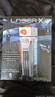 Photo of Laser X Gaming Tower in original box with branding and game features visible.