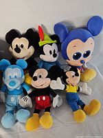 Six Mickey Mouse plush toys in different styles and colors placed closely together