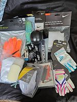 Wide shot of all items included in the lot showing various gloves, knee pads, and sports tapes.