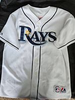 Front side of white Majestic Tampa Bay Rays baseball jersey showing full team logo and button-up front.