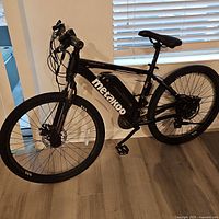 Full left-side profile of bike showing frame, battery, wheels, pedals and kickstand