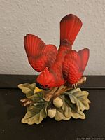 Front view of vintage Lefton hand-painted ceramic cardinal bird perched on a branch with leaves and acorns.