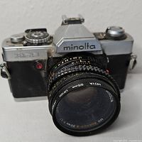 Front view of the Minolta XG9 camera showing the lens and body with branding and model name.