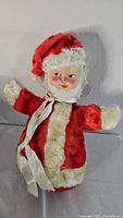 Full view of the vintage Santa plush showing the red and white outfit and plastic face.