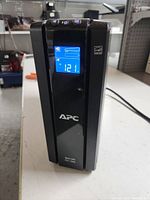 Front view of APC Back-UPS Pro 1500 UPS with digital display screen active showing voltage reading 121V.