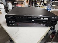 Front view of Apex AD-6511 DVD player showing control buttons, display, and headphone jack.