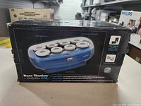 Photo of Babyliss Pro Nano Titanium hair roller set in box showing 8 rollers in blue base with control switch and indicator light.