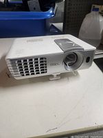 Front angle of white BenQ projector showing lens and vent grills.