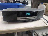 Front view of Bose Wave CD Player showing digital clock display with time 12:00 illuminated in blue-green LED.