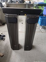 Full view of the three Bose speakers showing two floor standing speakers and one center channel speaker on top.