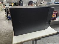 Side view of black Bose subwoofer showing fabric front and control knobs on the side panel