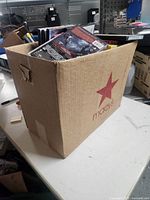 Full Macy's branded cardboard box filled with DVDs.