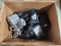 Top-down view of a cardboard box filled with several cameras and accessories.