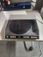 Closed view of the Denon turntable front showing control buttons and dust cover.