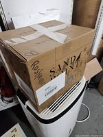 Closed box labeled Sandy with tape and writing, filled with DVDs inside.