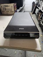 Front view of Epson scanner showing the brand name and buttons on the lower front panel.