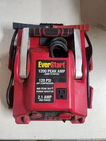 Top view of EverStart jump starter showing metal jumper clamps and label with specifications.