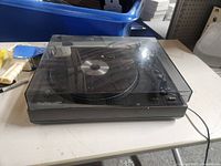 Side-angled view of the Fisher DC-servo stereo turntable showing dust cover, power cable, and overall external condition.