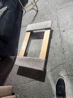 Top view of rectangular wooden furniture dolly with gray carpet padding strips on top surface to protect furniture.