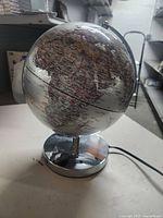 Photo of silver globe lamp showing the African continent detail and metallic base with attached power cord.