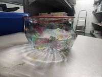 Side view of the hand blown glass bowl showing colorful swirls and red rim.