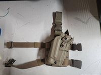 Front view of the tan Safariland hip holster with leg straps and retention locking system visible.