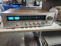 Front view showing illuminated tuning dial, signal meters, and control knobs on silver panel.