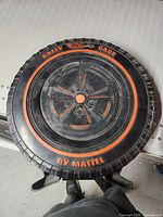 Top view of round black plastic Hotwheels Red Line Rally case with red lettering and tire tread design.