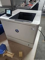 Front and side view of HP LaserJet Enterprise M609 printer showing physical condition and overall design.