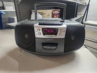 Front view of the Lenoxx Sound boombox showing speakers, display, cassette door, and control buttons.