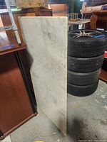 Side view of the white marble slab standing upright with visible irregularities and wood attachment.